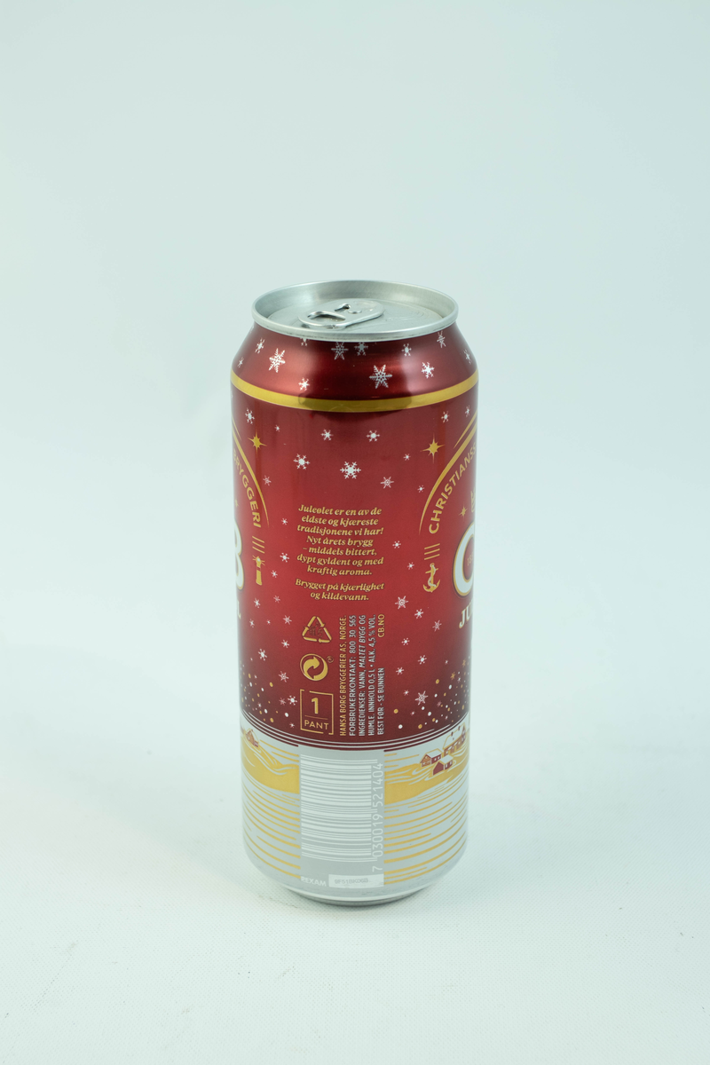 Rød aluminiumsboks med flerfarget logo og motiv. Gyllent fyrtån med hvite snødetaljer på rød bakgrunn