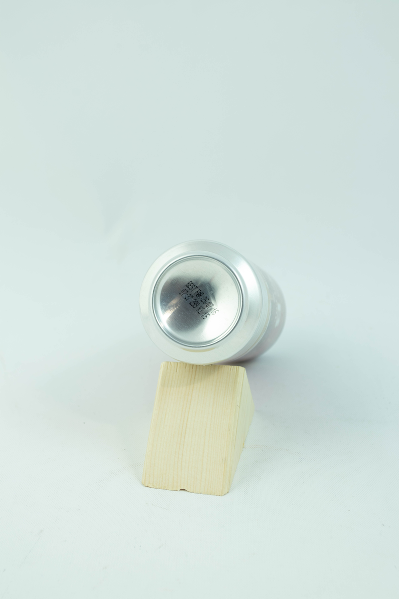 Rød aluminiumsboks med flerfarget logo og motiv. Gyllent fyrtån med hvite snødetaljer på rød bakgrunn