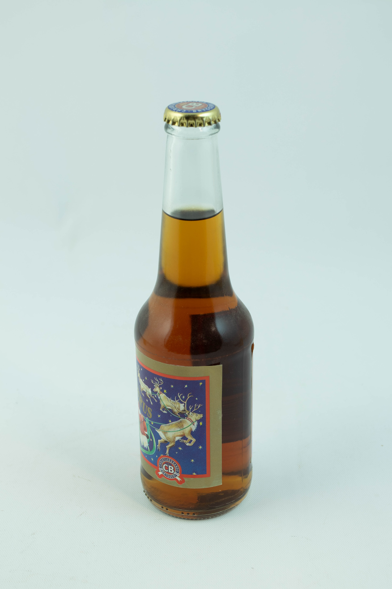 Klar glassflaske som har flerfarget etikett med julemotiv