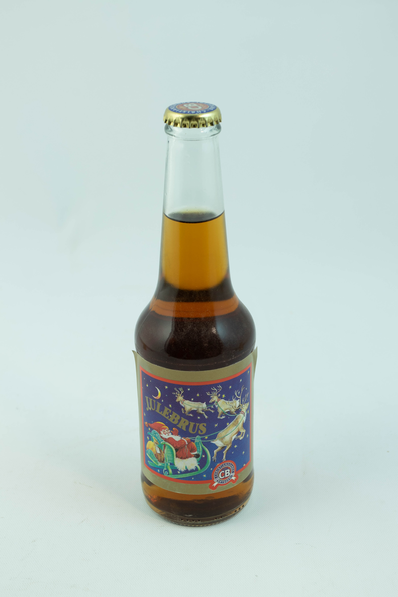 Klar glassflaske som har flerfarget etikett med julemotiv