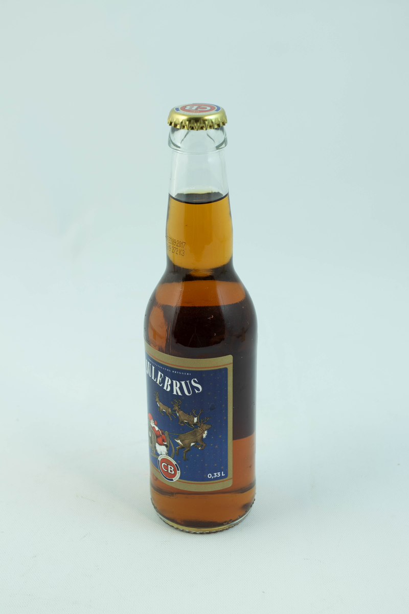 Klar glassflaske som har flerfarget etikett med julemotiv