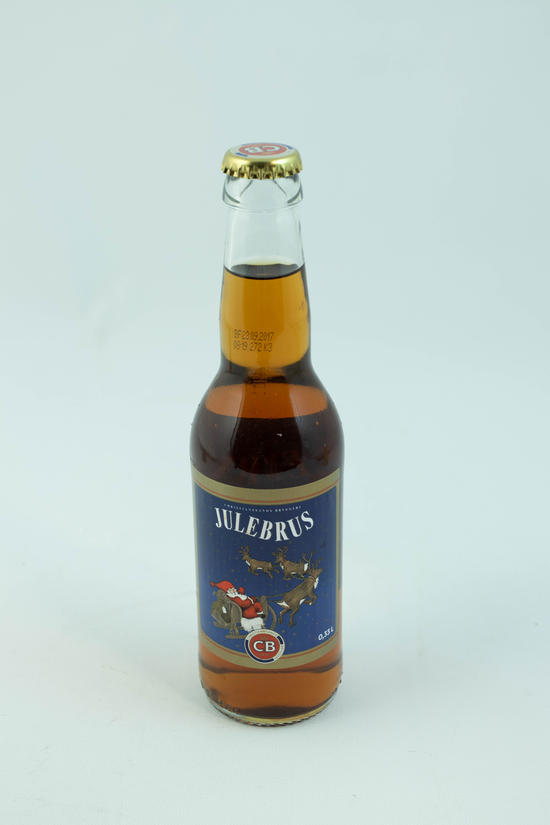 Klar glassflaske som har flerfarget etikett med julemotiv