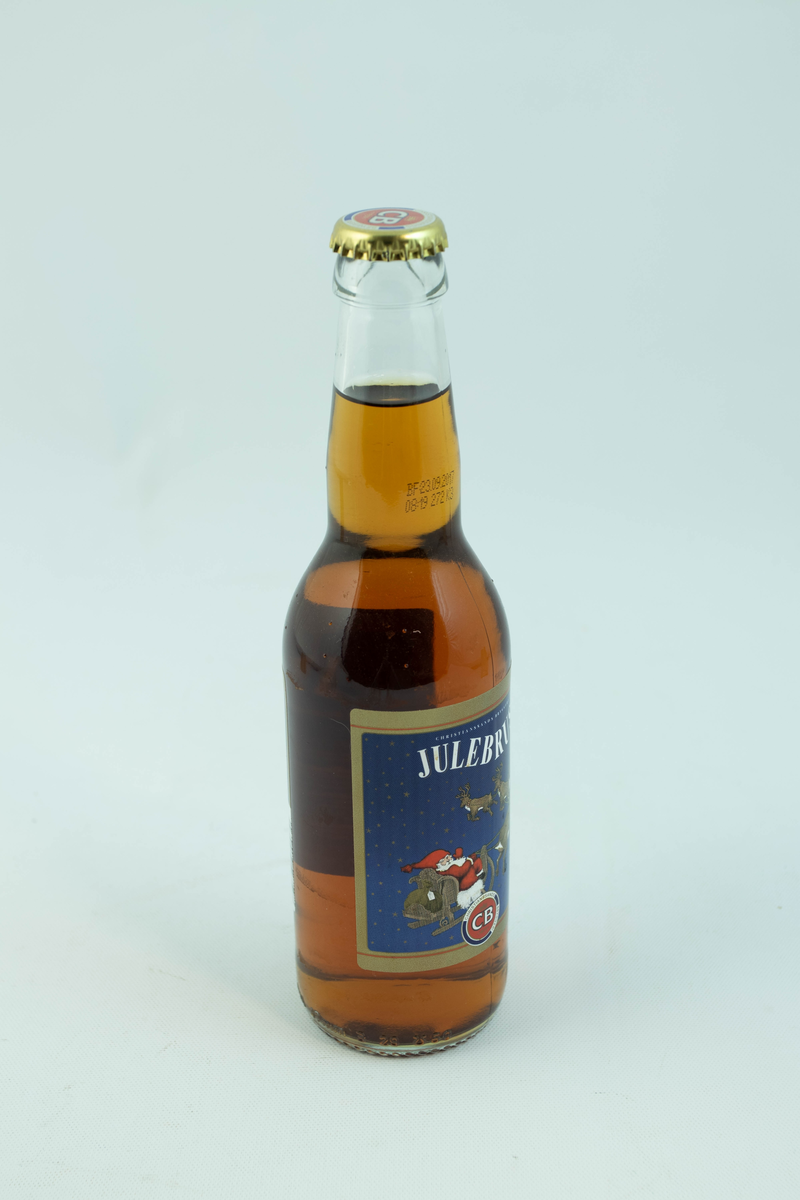 Klar glassflaske som har flerfarget etikett med julemotiv