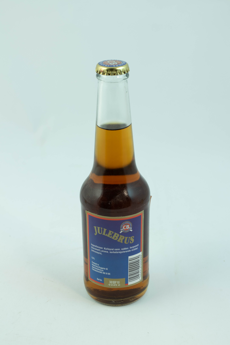 Klar glassflaske som har flerfarget etikett med julemotiv