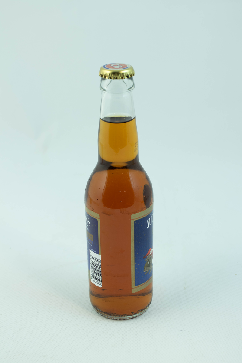 Klar glassflaske som har flerfarget etikett med julemotiv