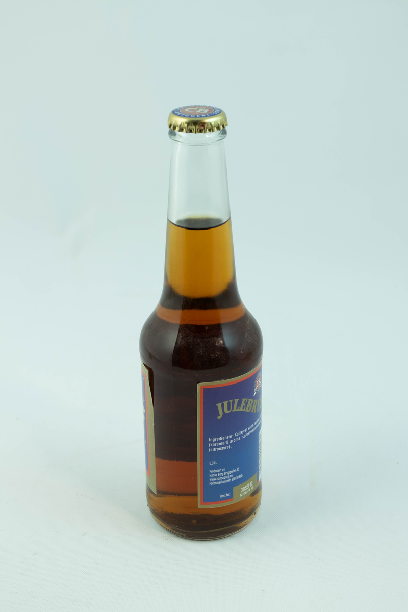 Klar glassflaske som har flerfarget etikett med julemotiv
