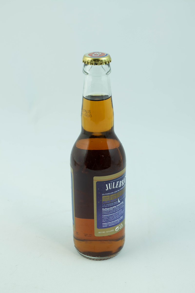 Klar glassflaske som har flerfarget etikett med julemotiv