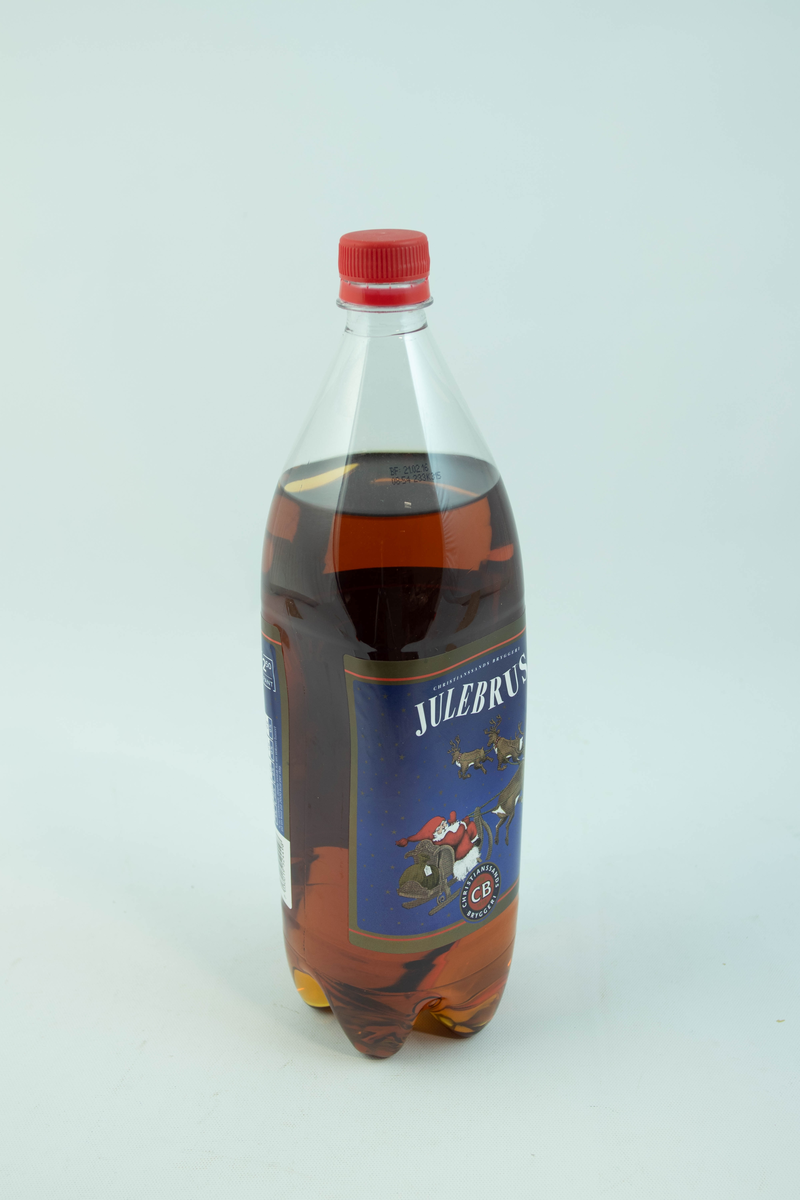 Stor klar glassflaske som har flerfarget etikett med julemotiv