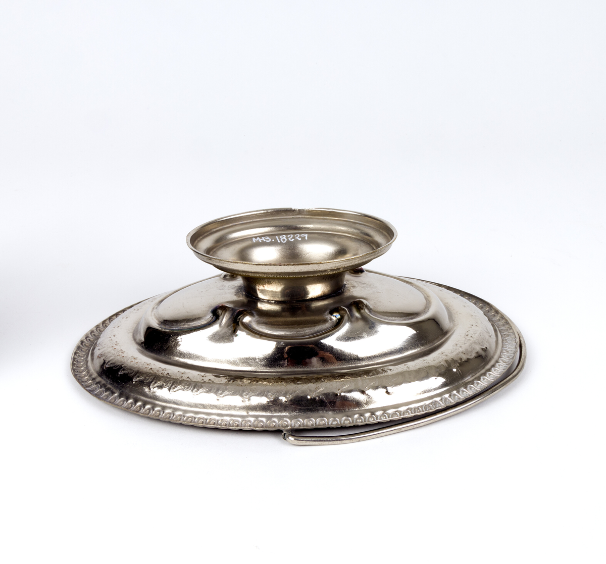 Skål. Oval og flat skål i form av en kurv, med håndtak og fot. Tynn metalltrådhåndtak fast på langsidene. Gravert dekor med plantemotiver med blomster og blader. Akantusblader som dekor midt i fatet.