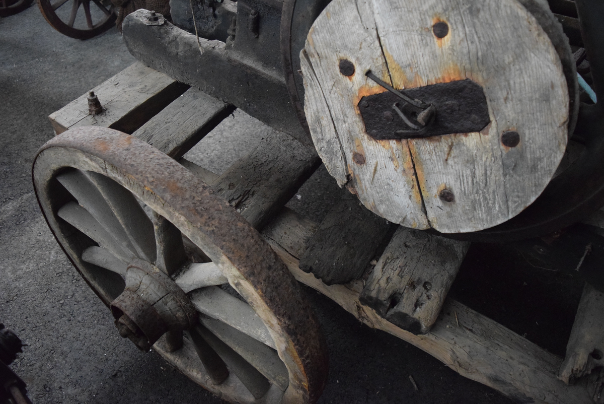 Maskin/motor montert på kjerre. Maskinen har to parallelle hjul på en aksling koblet til motoren. Lav kjerre med to hjul på aksling. Hjul av tre med 12 eiker og jernskoning. Trebord på tvers til å legge ting oppå.