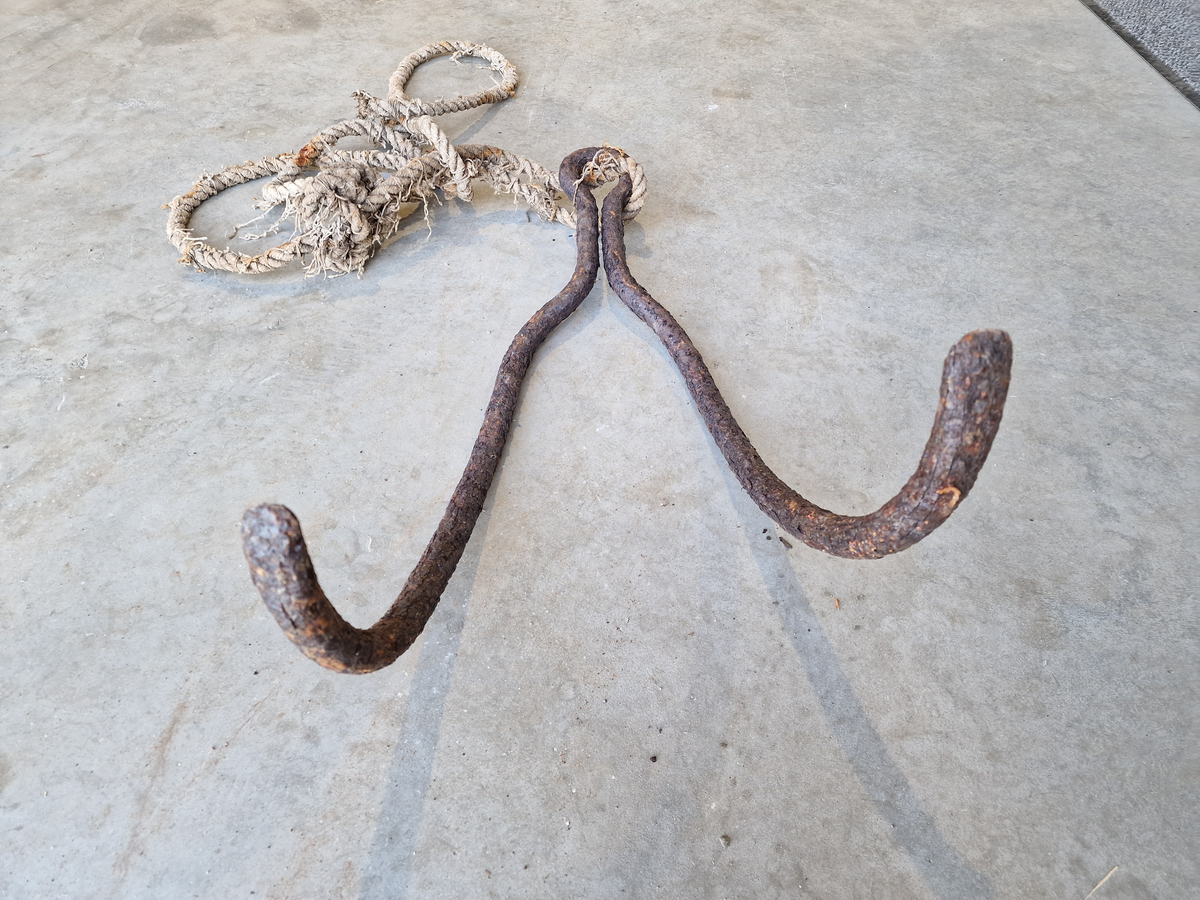 Metallstang, bøyd på midten og formet som to kroker som henger sammen med et "øye" (ikke helt rundt) til å feste tau i. Med tau.