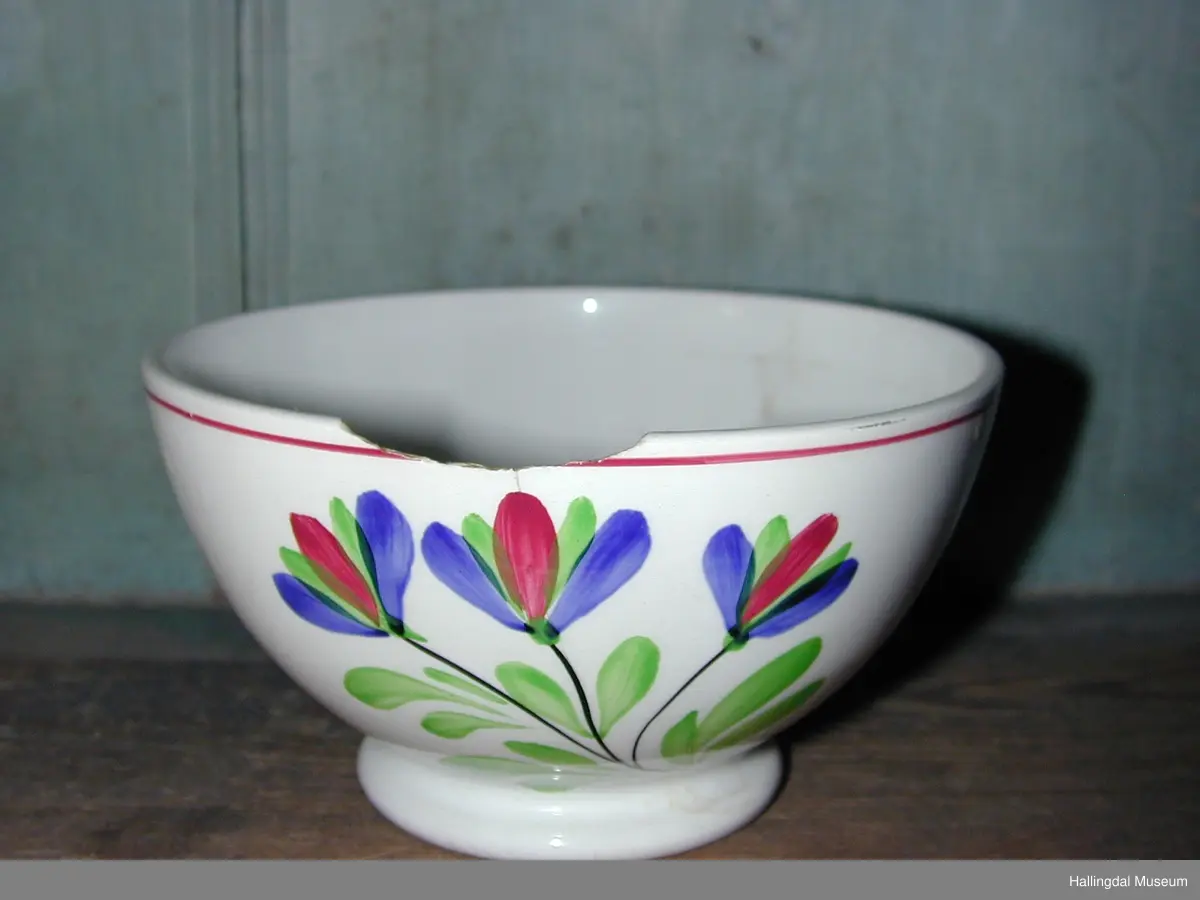 Bolle med rundt tverrsnitt. Lav fot. Hvit bunn med 3 like motiv, røde og blå blomster, sorte stilker og grønne blad.