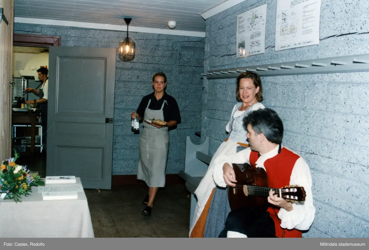 Venezuelas ambassadör Sadio Garavini di Turno besöker Gunnebo slott i Mölndal, juni 1999. Musikern Martin Bagge och en sångerska är i resturangens kapprum. Båda uppklädda. Paret underhöll gästerna under måltiden i restaurangen. En kvinna ur kökspersonalen kommer med mat och dryck.