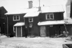 In på gården i vad som i Linköping var ett av Tannefors kvarter. Fotoåret 1926 hade en ny fastighetsindelning börjat införas i staden och just Tannefors kvarter erhöll kvadrater med namn på begynnelsebokstaven D. Området väster om Trädgårdstorget namngavs Delfinen och där hittar vi förklaringen till namngivningen av Definpalatset som sedan 1927 pryder torgets sida. På samma plats stod fotografen för att dokumentera tiden före husets tillkomst.