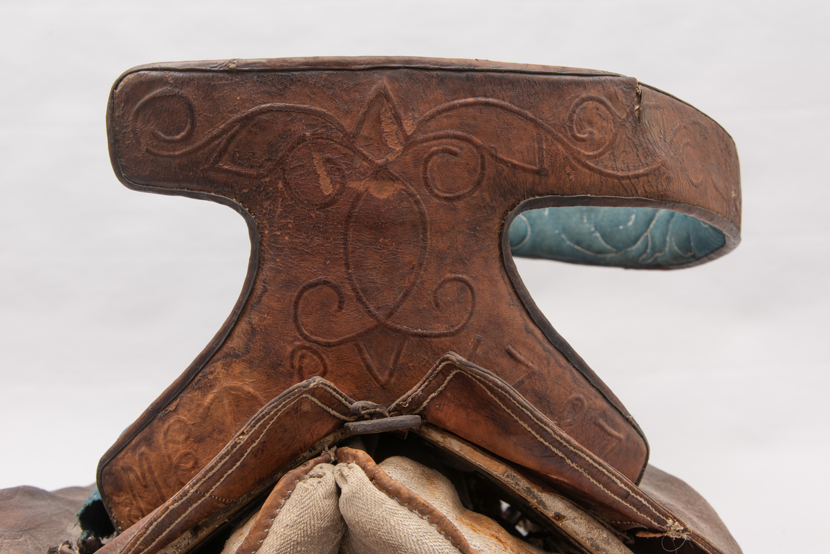 Håndlaget sal fra 1787. Bygd opp utifra en treform med lerret (strie). Pånaglet lær på sidene av stolen og på baksiden og yttersidene av selve stolen. Læret på den ene yttersiden av stolen er preget med inskripsjonen "1787 M.E.D.B." Stolen er innvendig fylt med stopp og trukket med grønt ullstoff som er påbrodert kruseduller. Læret er preget med en forenklet akantusranke. Salputen under er sydd i lerret (strie) og fylt med stopp, og festet kun på den ene siden. Alle remmene er i lær, nagler og spenner av jern.
