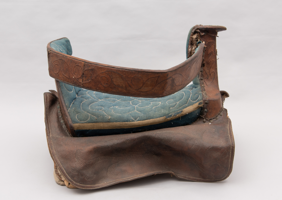 Håndlaget sal fra 1787. Bygd opp utifra en treform med lerret (strie). Pånaglet lær på sidene av stolen og på baksiden og yttersidene av selve stolen. Læret på den ene yttersiden av stolen er preget med inskripsjonen "1787 M.E.D.B." Stolen er innvendig fylt med stopp og trukket med grønt ullstoff som er påbrodert kruseduller. Læret er preget med en forenklet akantusranke. Salputen under er sydd i lerret (strie) og fylt med stopp, og festet kun på den ene siden. Alle remmene er i lær, nagler og spenner av jern.