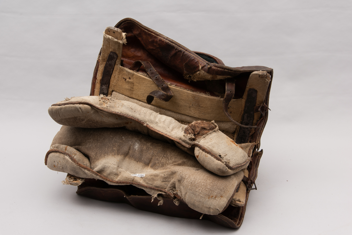 Håndlaget sal fra 1787. Bygd opp utifra en treform med lerret (strie). Pånaglet lær på sidene av stolen og på baksiden og yttersidene av selve stolen. Læret på den ene yttersiden av stolen er preget med inskripsjonen "1787 M.E.D.B." Stolen er innvendig fylt med stopp og trukket med grønt ullstoff som er påbrodert kruseduller. Læret er preget med en forenklet akantusranke. Salputen under er sydd i lerret (strie) og fylt med stopp, og festet kun på den ene siden. Alle remmene er i lær, nagler og spenner av jern.
