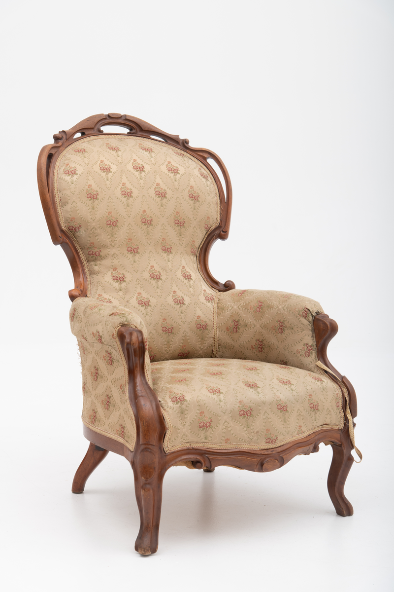 Gruppe med sofa, to lenestoler og tre mindre stoler uten armlener i stilen nyrokokko. Gyllengult trekk med rosemotiv og mørkt treverk med buede, organiske linjer.
