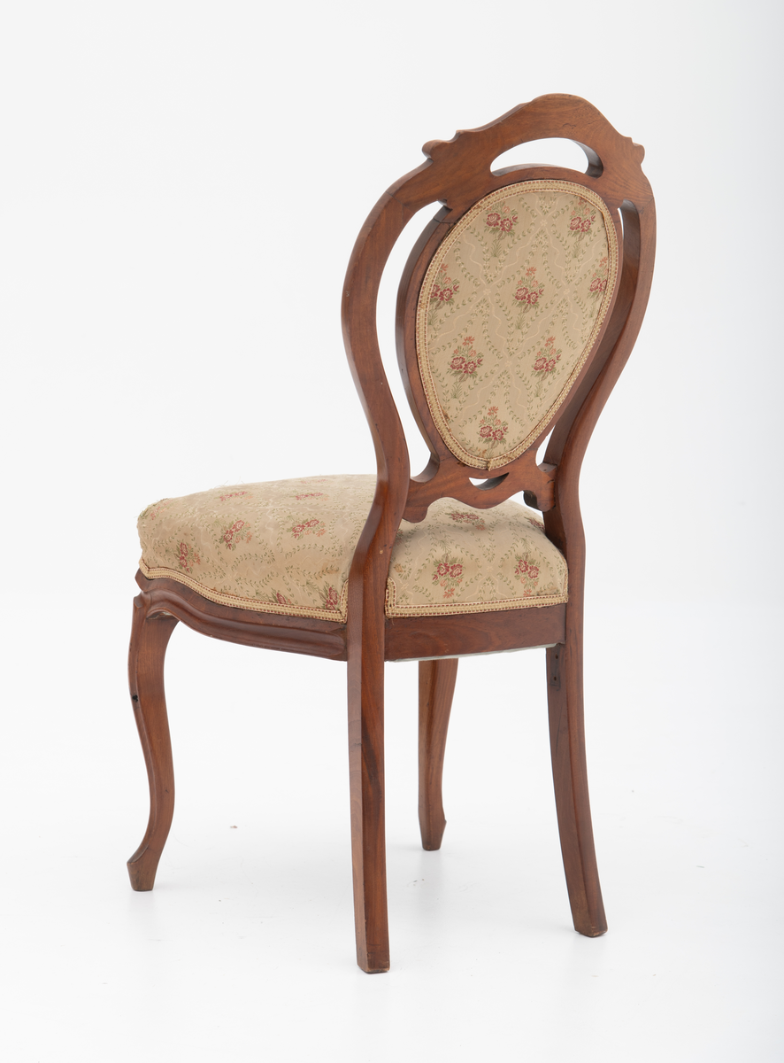 Gruppe med sofa, to lenestoler og tre mindre stoler uten armlener i stilen nyrokokko. Gyllengult trekk med rosemotiv og mørkt treverk med buede, organiske linjer.

