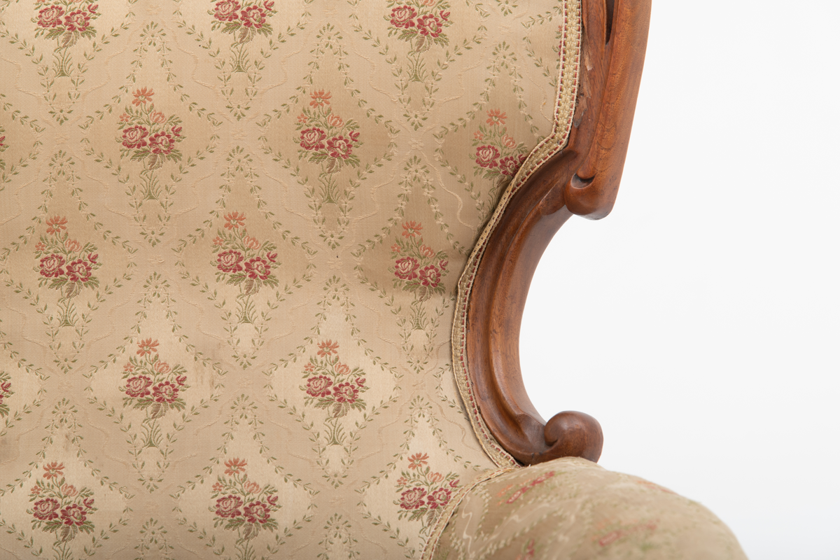 Gruppe med sofa, to lenestoler og tre mindre stoler uten armlener i stilen nyrokokko. Gyllengult trekk med rosemotiv og mørkt treverk med buede, organiske linjer.
