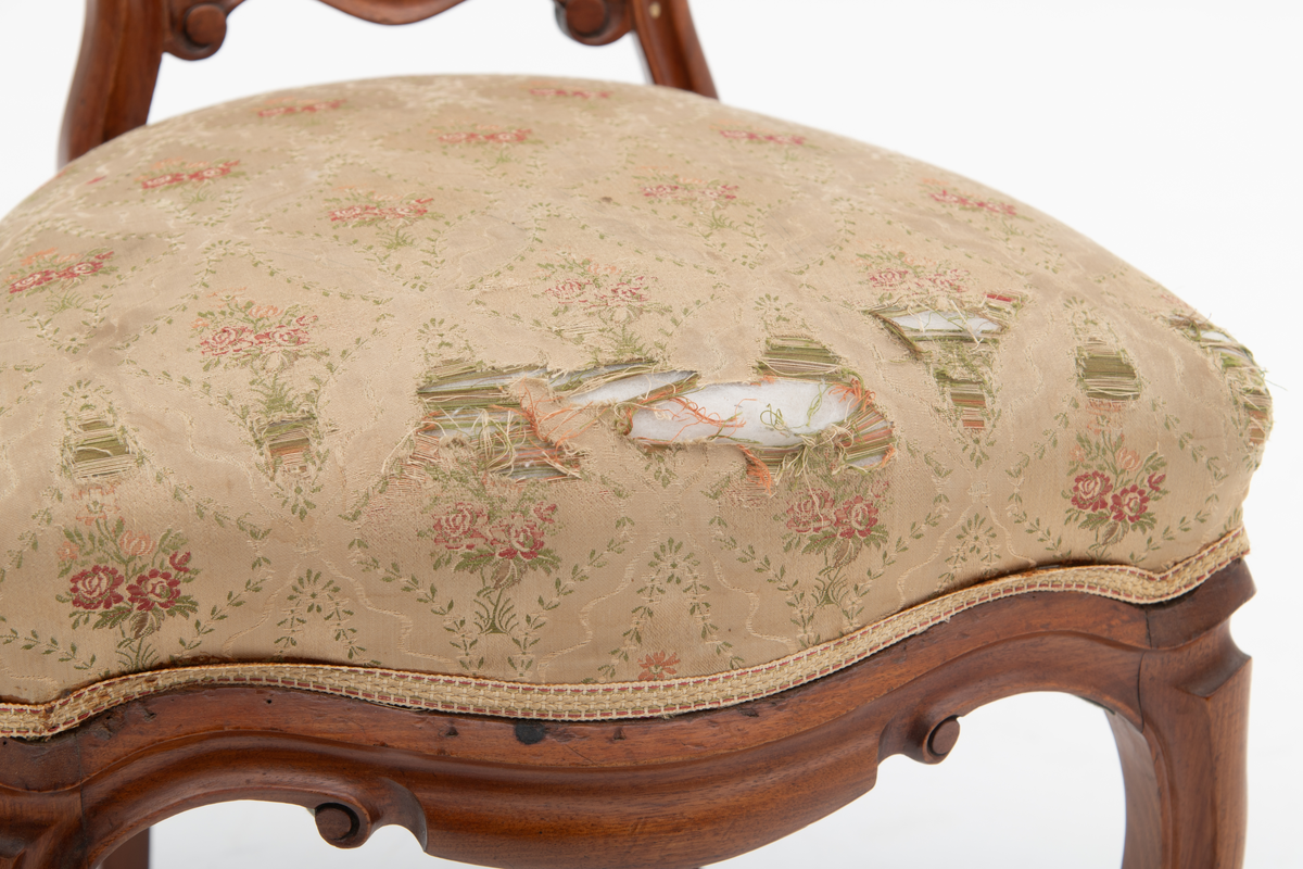 Gruppe med sofa, to lenestoler og tre mindre stoler uten armlener i stilen nyrokokko. Gyllengult trekk med rosemotiv og mørkt treverk med buede, organiske linjer.
