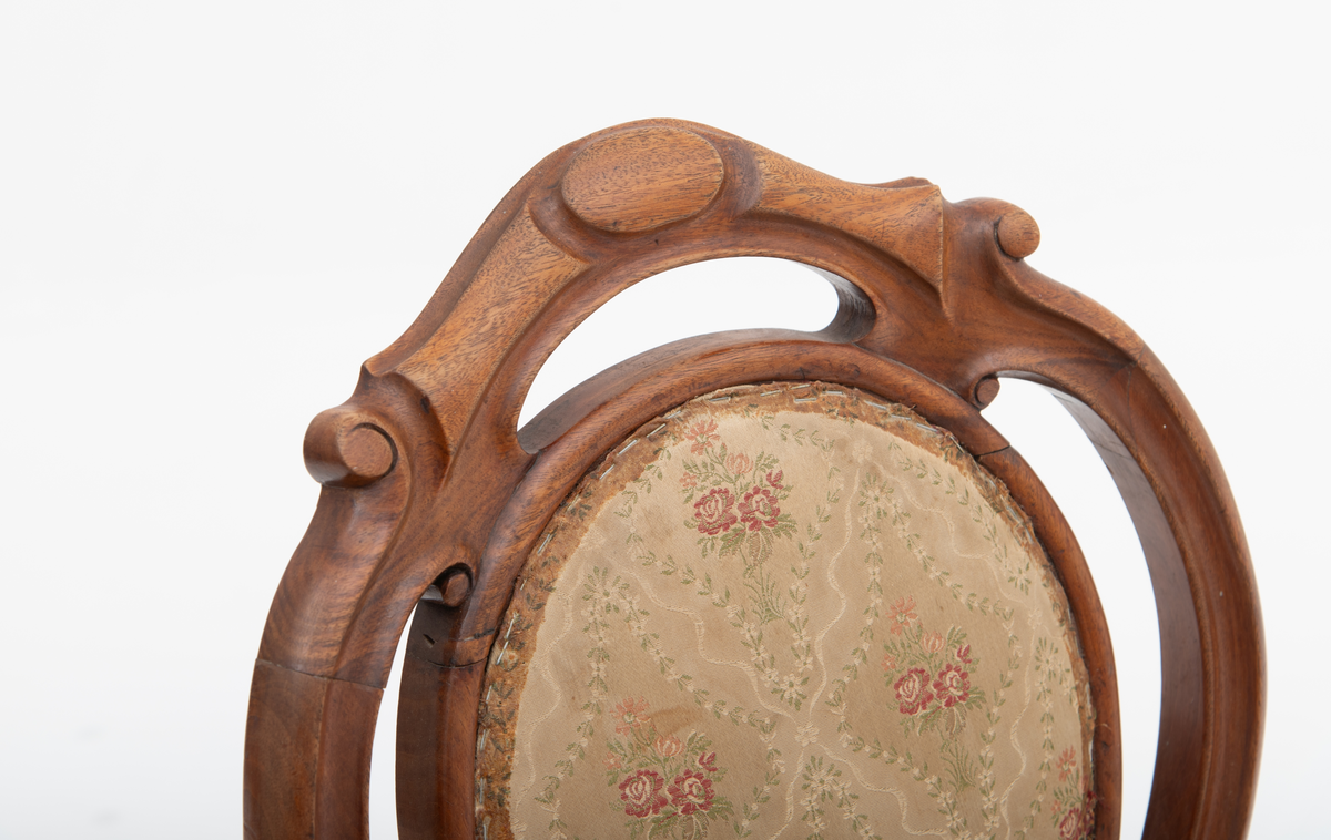 Gruppe med sofa, to lenestoler og tre mindre stoler uten armlener i stilen nyrokokko. Gyllengult trekk med rosemotiv og mørkt treverk med buede, organiske linjer.
