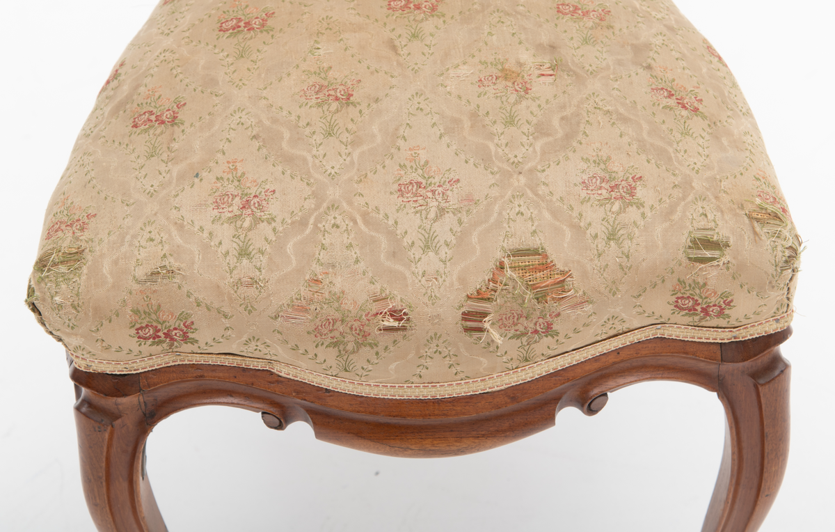 Gruppe med sofa, to lenestoler og tre mindre stoler uten armlener i stilen nyrokokko. Gyllengult trekk med rosemotiv og mørkt treverk med buede, organiske linjer.
