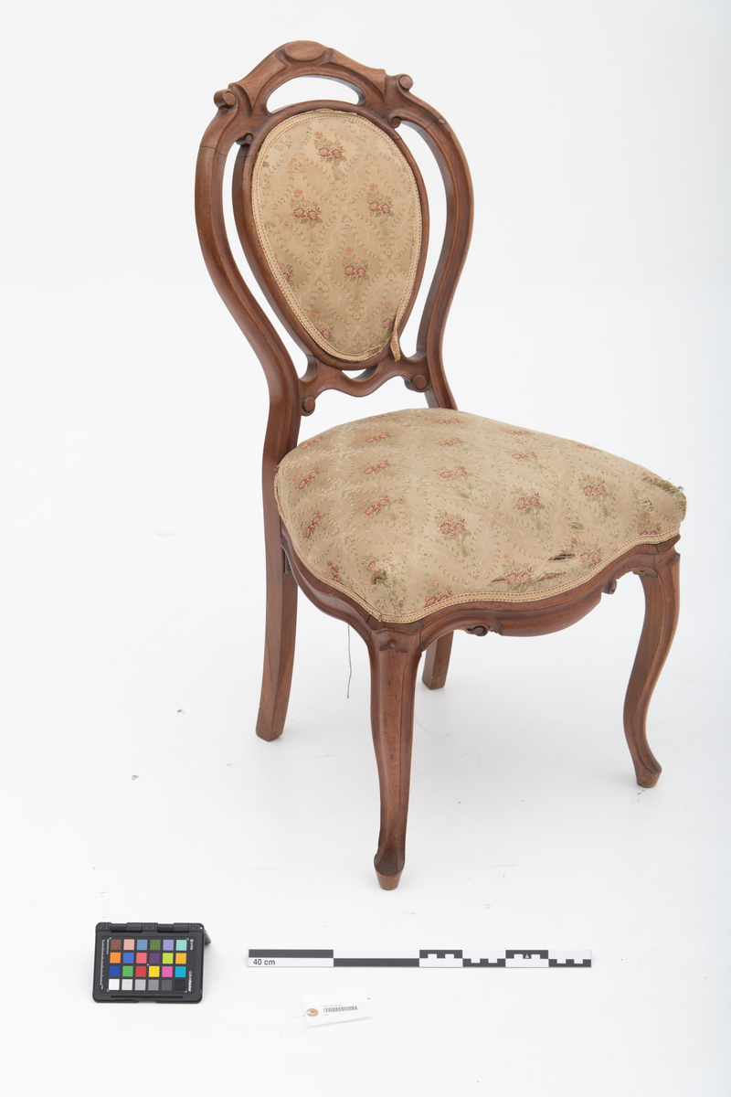 Gruppe med sofa, to lenestoler og tre mindre stoler uten armlener i stilen nyrokokko. Gyllengult trekk med rosemotiv og mørkt treverk med buede, organiske linjer.
