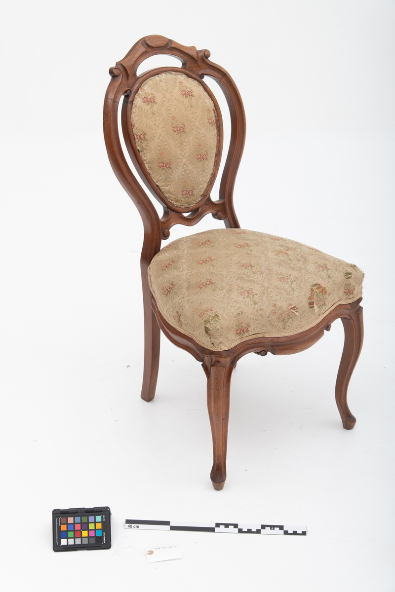 Gruppe med sofa, to lenestoler og tre mindre stoler uten armlener i stilen nyrokokko. Gyllengult trekk med rosemotiv og mørkt treverk med buede, organiske linjer.
