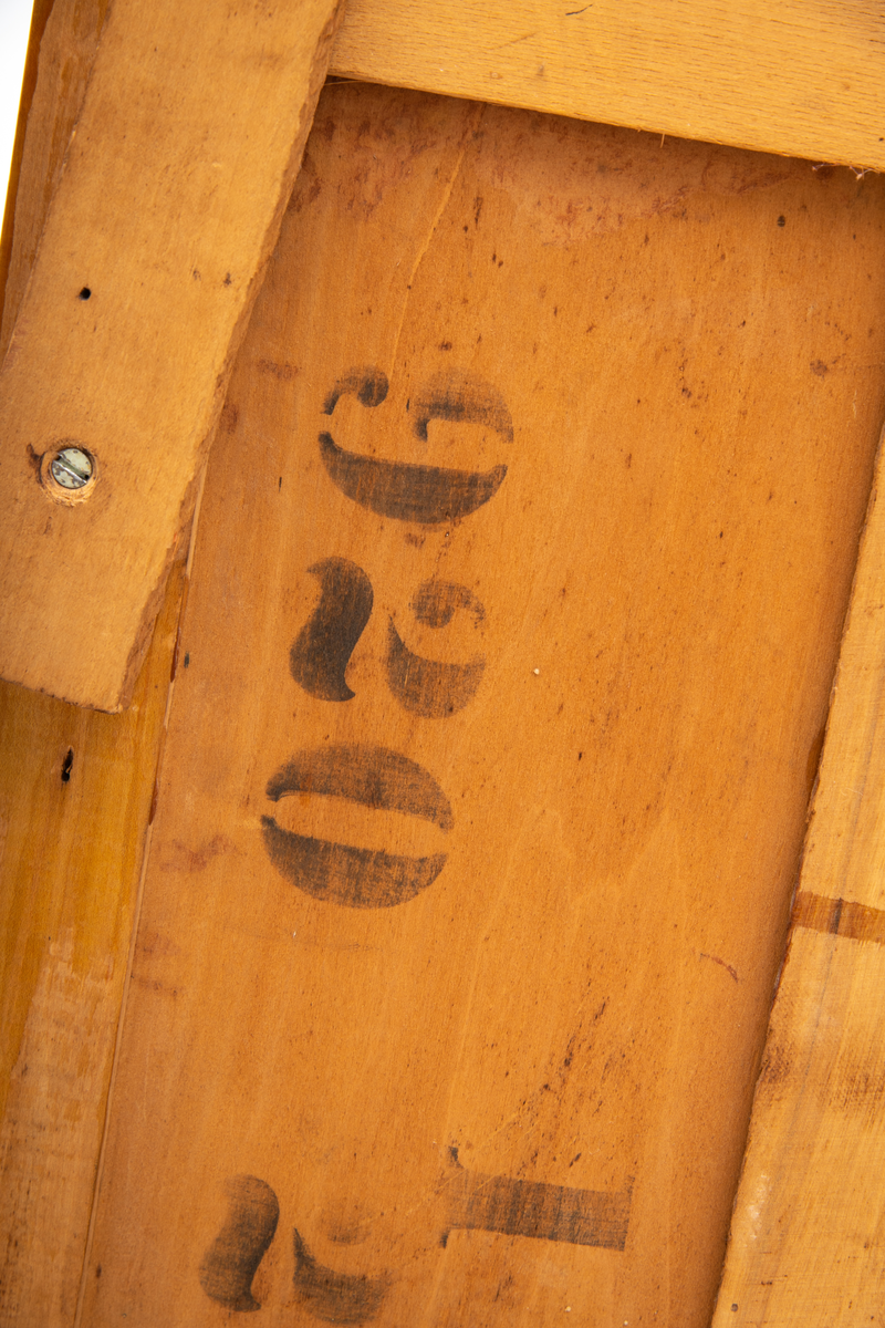 Kommode. Topplate og fronten på kommoden er bølget i formen. To mindre skuffer øverst, og en stor låsbar skuff nederst. Treknotter. Ben med hjul.