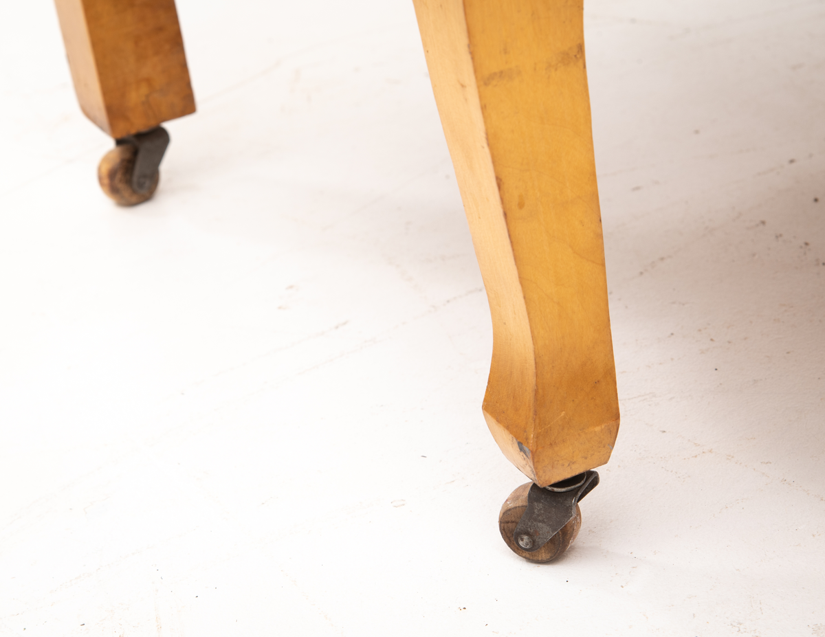 Kommode. Topplate og fronten på kommoden er bølget i formen. To mindre skuffer øverst, og en stor låsbar skuff nederst. Treknotter. Ben med hjul.