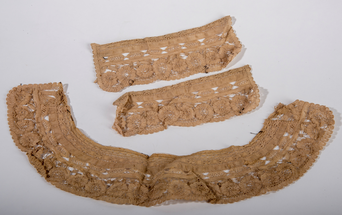 Blondekrage og tilhørende mansjetter. Beige i fargen. Border og blomstermotiv.