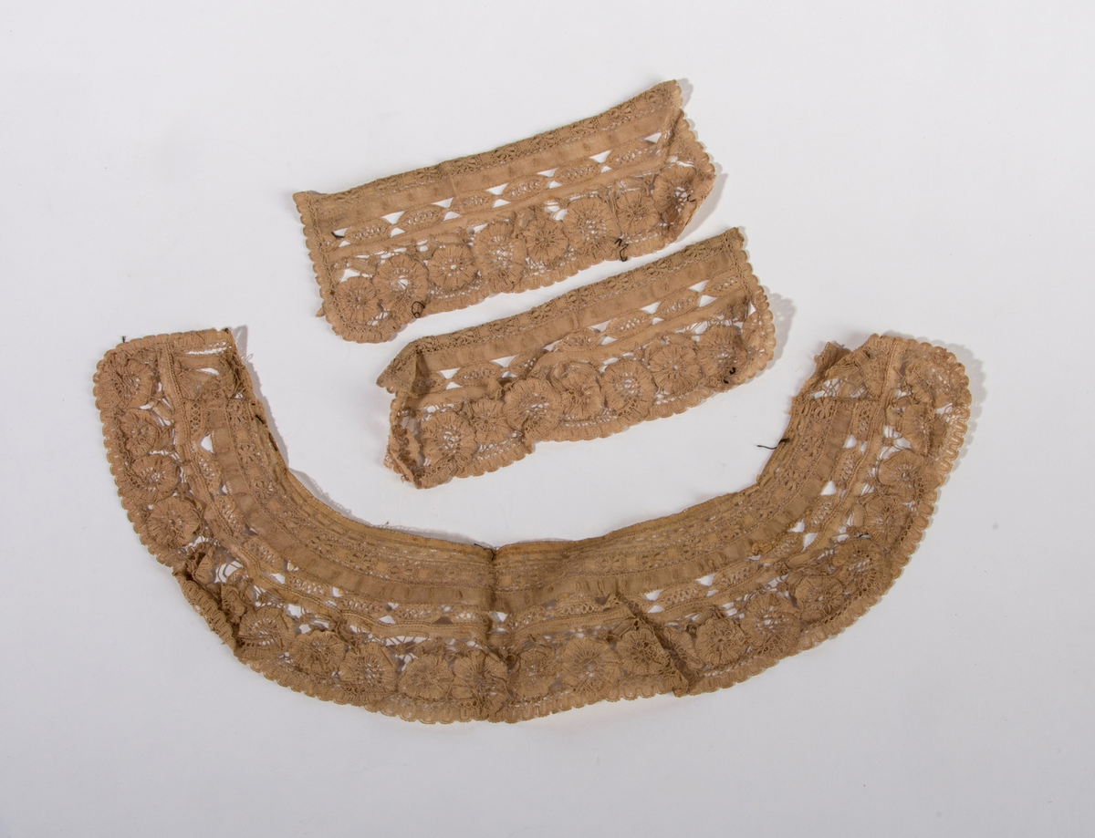 Blondekrage og tilhørende mansjetter. Beige i fargen. Border og blomstermotiv.