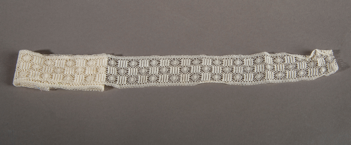 Blonderemse. Hvit. Rette kanter på hver side. Motivet er satt sammen av sirkler og kvadrater(staver), forskjøvet i forhold til hverandre slik at det danner tre border.