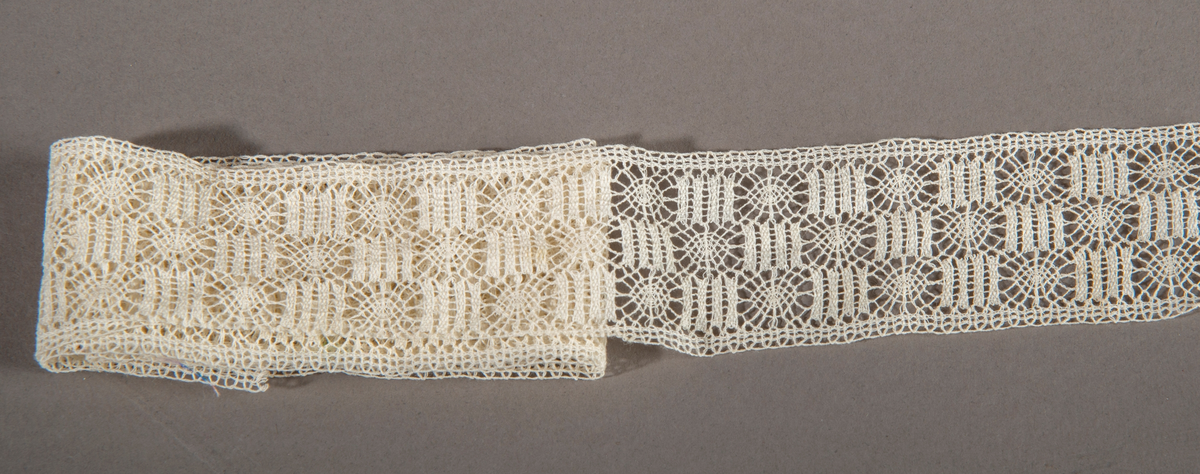 Blonderemse. Hvit. Rette kanter på hver side. Motivet er satt sammen av sirkler og kvadrater(staver), forskjøvet i forhold til hverandre slik at det danner tre border.