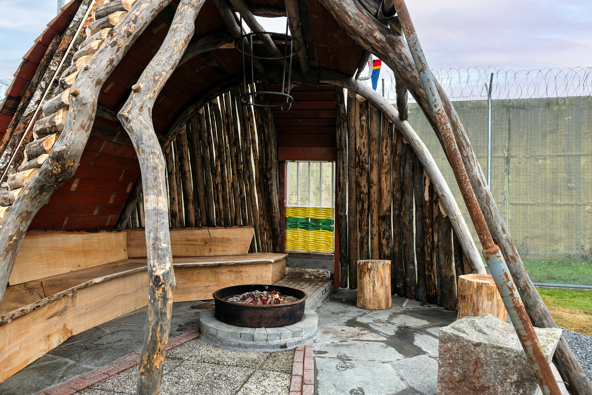 Tekst på nordsamisk lenger ned / Geahca sámegiela teavstta vuolábealde

"Flukthus/Báhtarangoahti" er et kunstverk utført av Vuogas, arkitekturkollektivet med kunstnerne og arkitektene Joar Nango og Eystein Talleraas, i nært samarbeid med innsatte og ansatte ved Ila. Verket har formen og funksjonen til en gamme, men er ikke bygget helt slik en gamme tradisjonelt blir bygget. Hovedstrukturen og de bærende elementene er tilvirket og satt sammen på tradisjonelt vis, men uten jord, torv og never slik det samiske folket gjennom tidene har benyttet seg av. Som vanlig når Vuogas engasjeres i prosjekter, har de undersøkt, funnet og brukt lokale materialer som bærer med seg historikken fra stedet. I dette tilfellet trevirke fra skogen rundt Ila, i tillegg til funnet materiale og gjenstander fra fengselet og gartneriets område. "Flukthus/Báhtarangoahti" er et arkitektonisk kunstverk, men også et oppholdssted og et sosialt rom. Det er bygget for avdelingen, med tanke for de innsatte og ansatte ved NFFA, og der intensjonen har vært at gammen og bålplassen skal bli et godt sted å være.

Joar Nango (f. 1979) er en samisk-norsk kunstner og arkitekt som bor og jobber i Tromsø. Han er utdannet arkitekt fra NTNU i Trondheim og grunnlegger av arkitekturkollektivet Vuogas sammen med Eystein Talleraas (f. 1980). Talleraas bor og jobber i Oslo, og er utdannet arkitekt fra NTNU i Trondheim.

"Báhtarangoahti/Flukthus" lea dáiddadagus, man Vuogas, dáiddára ja arkiteavtta guoktá Joar Nango ja Eystein Talleraas arkitektuvrakollektiiva lea ráhkadan, lagas ovttasbarggus Ila giddagasa fá¿ggaiguin ja virggehasaiguin.  Dáiddadahkosis lea goadi hápmi ja doaibma, muhto dat ii leat huksejuvvon jur dego goahti árbevirolaccat huksejuvvo. Riggi ja válddahagat leat ávdnejuvvon ja cohkkejuvvon árbevirolaš vuogi mielde, muhto goadis eai leat lavnnjit, darffit ja beassit, maid sápmelaccat áiggiid cada leat geavahan godiineaset. Nugo dábálaccat go Vuogas bálkáhuvvo prošeavttaide, de lea arkiteaktakollektiiva guorahallan, gávdnan ja geavahan báikkálaš ávdnasiid, main lea lagasbirrasa historihkka. Dán oktavuodas lea ávnnasmuorat vižžojuvvon vuovddis Ila birra, ja lassin leat gávdnon ávdnasat ja biergasat giddagasas ja gilvvagárdedoalu guovllus. "Báhtarangoahti/Flukthus" lea arkitektuvrralaš dáiddadagus, muhto maiddái orostallansadji ja servvoštallanlatnja. Dat lea huksejuvvon ossodaga várás, NFFA [našuvnnalaš nannejuvvon oktasašossodaga] fá¿ggaid ja virggehasaid gorrái, ja man áigumuš  lea leamaš ahte goahti ja árran galget šaddat sadjin gos lea vuogas leahkit.

Joar Nango (r. 1979) lea Norgga beali sámi dáiddár ja arkiteakta, gii ássá ja bargá Romssas. Son lea oahppan arkiteaktan NTNU:s [Norgga teknihkalaš-luonddudiedalaš universiteahtas] Tråantes/Troanddimis, ja lea vuoddudan Vuogas arkitektuvrakollektiivva ovttas Eystein Talleraas:in (r. 1980). Talleraas ássá ja bargá Osloves, ja lea oahppan arkiteaktan NTNU:s Tråantes/Troanddimis.