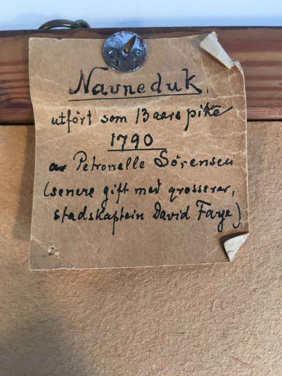 Navneduk brodert, med ramme. Tekst bak på ramme. 1790