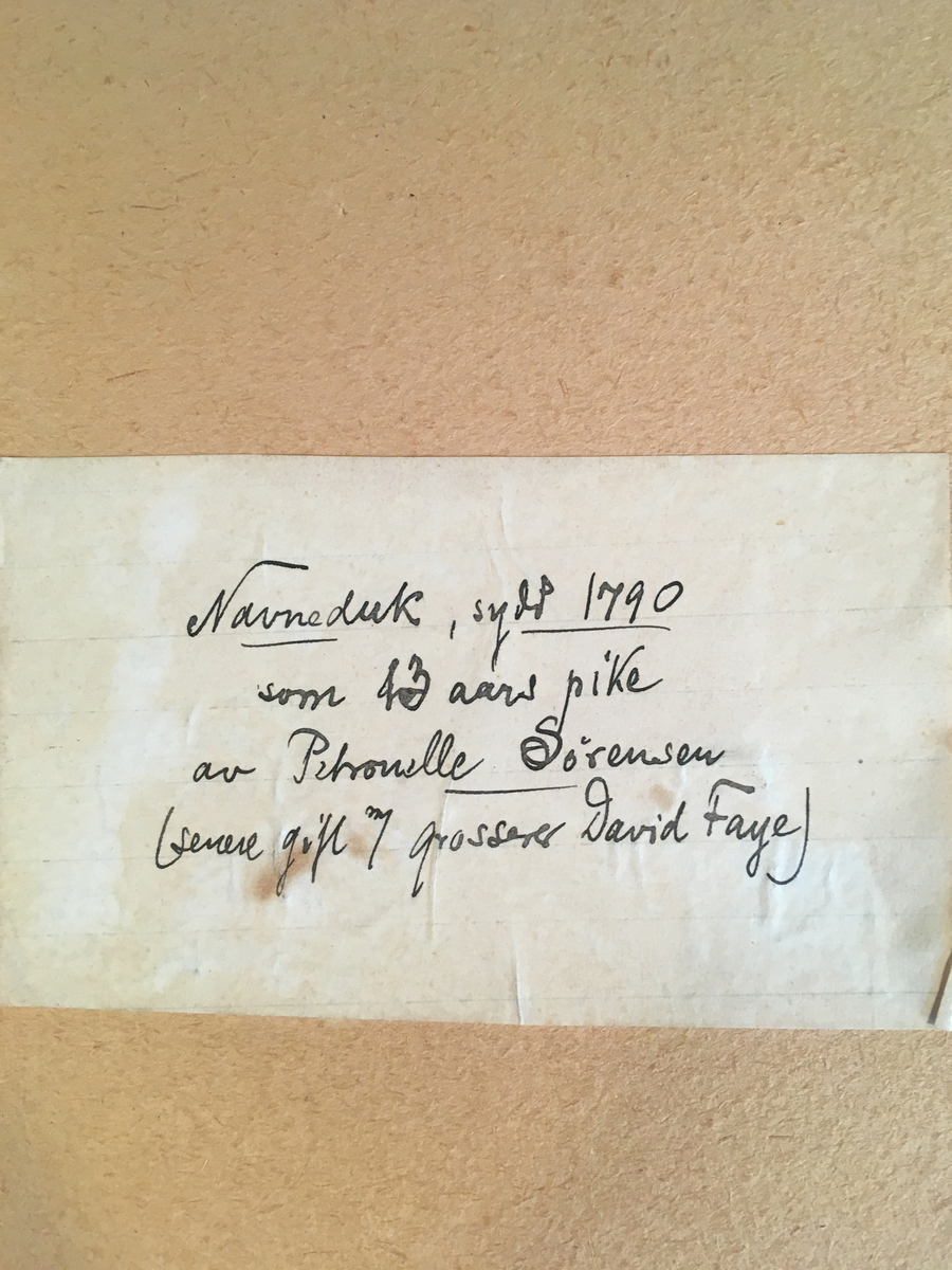 Navneduk brodert, med ramme. Tekst bak på ramme. 1790