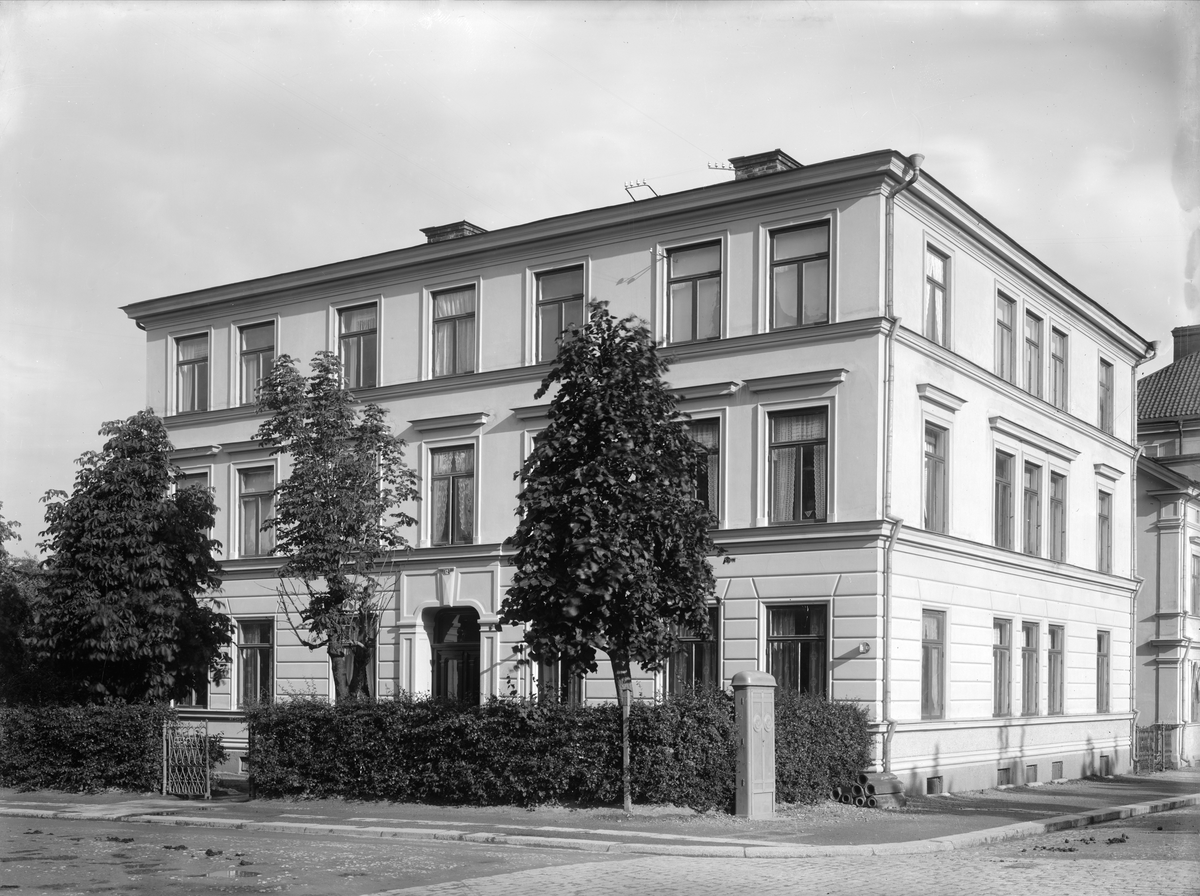 Vy mot Linnégatan 12 i Linköping. Huset byggdes 1883 av byggmästarna Anders Ohlsson och Anders Gustaf Johansson. Efter färdigställandet valde de att bosätta sig i huset med sina respektive familjer. När Ohlsson flyttade 1886 sålde han sin del i huset till Johansson, som för egen del bodde kvar till 1895 då han färdigställt huset mittemot (S:t Larsgatan 43B) och flyttade dit. Huset revs 1968. Dessförinnan hade fastigheten efter beslut om adressomvandling erhållit gatunummer 10. Bilden är odaterad och svår att tidsbestämma. Vi skriver omkring 1925.
