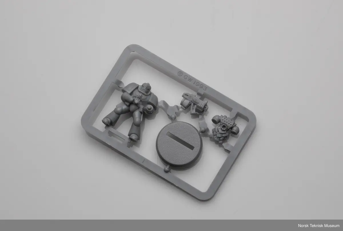 Dette er 2 eldre "Space marine" modeller som brukes i spillet Warhammer 40,000. Figuren ble gitt som gave til museet i forbindelse med utstillingen "Modeller og Miniatyrer" i 2024. Den ene modellen er satt sammen og den andre er fortsatt på støperamme. Støperammen til den sammensatte figuren er en del av gjenstanden.

Den avbildede støpeformen er original men er ikke en del av gjenstanden. Den var et innlån fra produsent ved aksesjon.