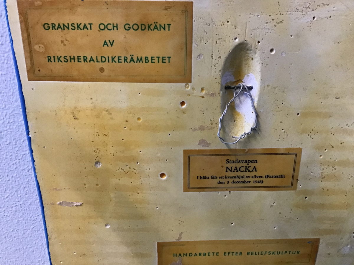 Nackas kommunvapen - kvarnhjulet, i gips. 20 centimeter brett och 25 centimeter högt. 