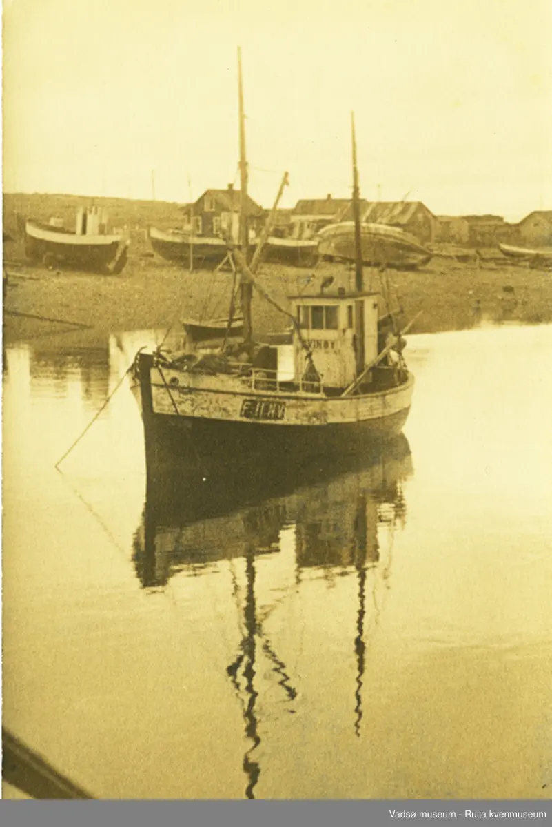 Båten F11 NV, Svinøy ved kaia i Vestre Jakobselv. Andre båter ligger på land. Ant. idten av 1950-tallet