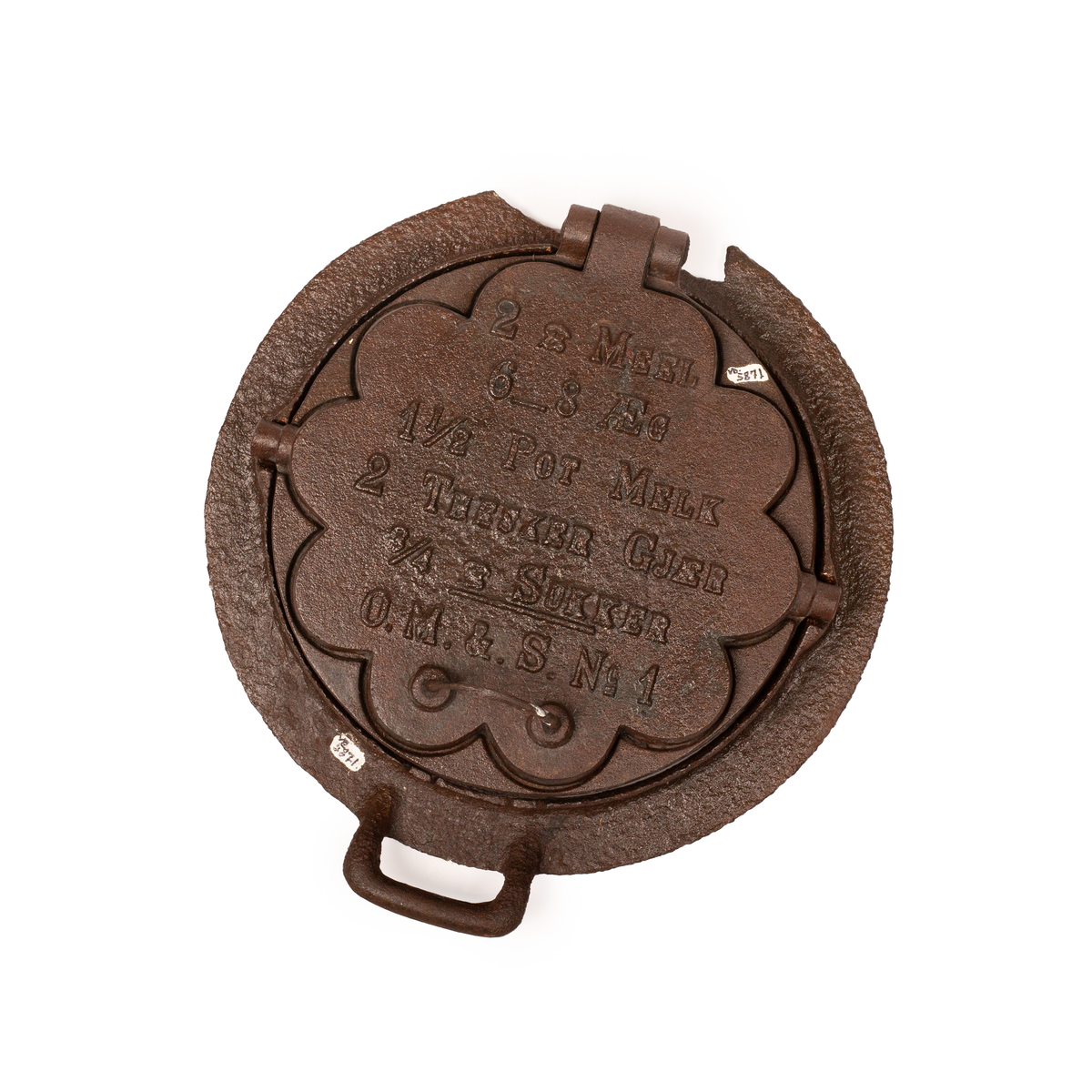 Kakejern for vafler produsert i støpejern. Jernet lager vafler med fem hjerter. Jernet er tilpasset ringkomfyren og har en ramme rundt som settes på kanten av hulle i komfyren. Jernet kan snus 180 grader rundt sin egen akse ved hjelp av to sylindere som hviler på spor i rammen.  

Jernet åpnes ved hjelp av et håndtak festet i en av endene på oversiden av lokket. På motsatt side er det et en hengsel som fester over og undersiden av jernet sammen. På lokket er det også støpt inn en oppskrift på vafler. Rammen til jernet har et håndtak i ene enden. På motsatt side er det en tydelig skade i rammen som tilsier at det har vært et identisk håndbak også her. 

Jernet viser tydelige tegn på rust grunnet oksidering. 