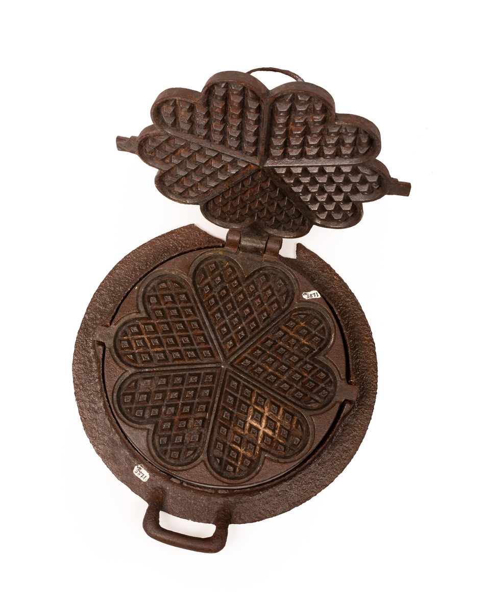 Kakejern for vafler produsert i støpejern. Jernet lager vafler med fem hjerter. Jernet er tilpasset ringkomfyren og har en ramme rundt som settes på kanten av hulle i komfyren. Jernet kan snus 180 grader rundt sin egen akse ved hjelp av to sylindere som hviler på spor i rammen.  

Jernet åpnes ved hjelp av et håndtak festet i en av endene på oversiden av lokket. På motsatt side er det et en hengsel som fester over og undersiden av jernet sammen. På lokket er det også støpt inn en oppskrift på vafler. Rammen til jernet har et håndtak i ene enden. På motsatt side er det en tydelig skade i rammen som tilsier at det har vært et identisk håndbak også her. 

Jernet viser tydelige tegn på rust grunnet oksidering. 