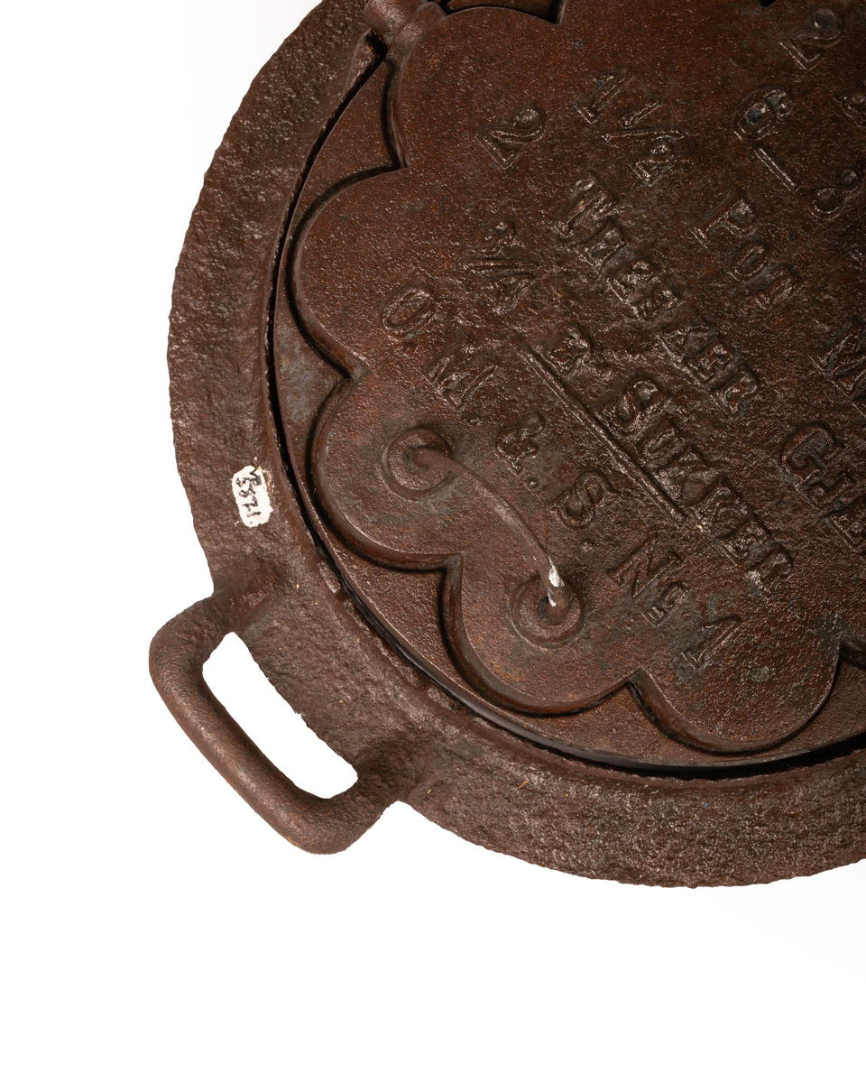 Kakejern for vafler produsert i støpejern. Jernet lager vafler med fem hjerter. Jernet er tilpasset ringkomfyren og har en ramme rundt som settes på kanten av hulle i komfyren. Jernet kan snus 180 grader rundt sin egen akse ved hjelp av to sylindere som hviler på spor i rammen.  

Jernet åpnes ved hjelp av et håndtak festet i en av endene på oversiden av lokket. På motsatt side er det et en hengsel som fester over og undersiden av jernet sammen. På lokket er det også støpt inn en oppskrift på vafler. Rammen til jernet har et håndtak i ene enden. På motsatt side er det en tydelig skade i rammen som tilsier at det har vært et identisk håndbak også her. 

Jernet viser tydelige tegn på rust grunnet oksidering. 