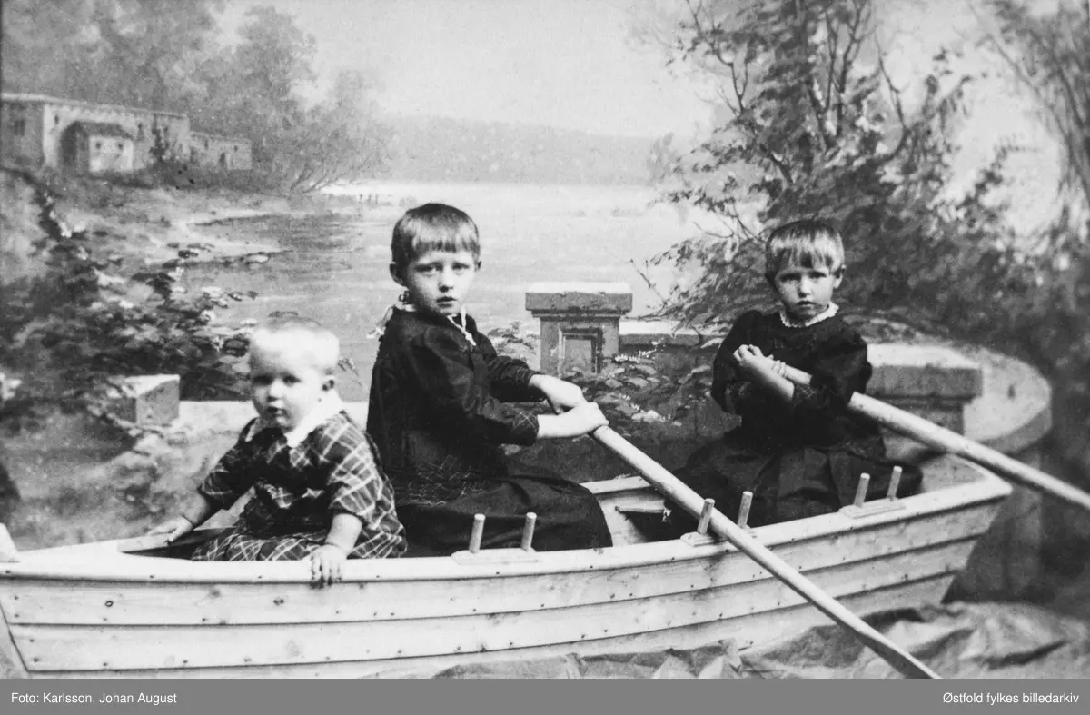Fotoatelierbilde av tre ukjente gutter i robåt, antakelig fra Varteig? ca.1900-10?