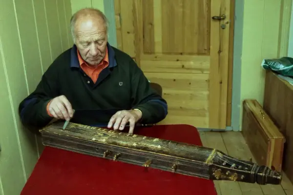 Mann spiller på eldre langeleik.