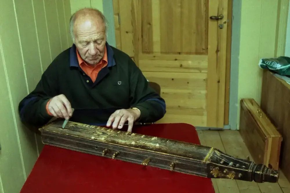 Mann spiller på eldre langeleik.