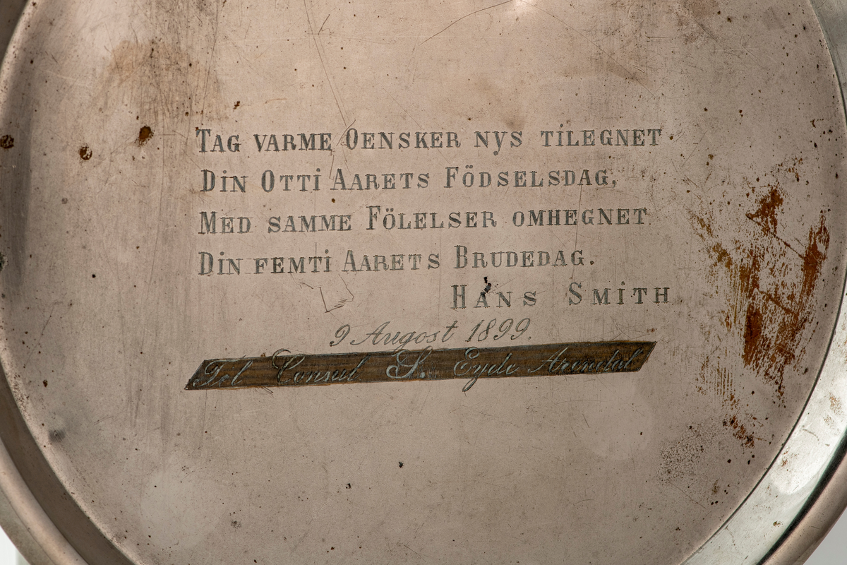 Samovar. Rund fot på fire utskrånende føtter. Stett med gjennombrutt dekor. Korpus med sider med rifler og avlange fasetter. To runde, tverr-riflede hanker av ben. Profilert overstykke med to benknotter. Ovalt fabrikkmerke med russisk tekst. Toppstykke med tre gjennombrutte ornamenter, nedsenket tungt lokk med ben-knott. Kran nederst på korpus, åpning i bunnen, og liten åpning for damp på overstykket.

Pipe. Forkrommet, skaft av messing og ben. Høy sylinderformet med utskrådd fotstykke, uten bunn, stjerthank.

Dryppskål av messing, utvendig forkrommet. Skål på stett. Midt i bunnen innvendig er det et ovalt firmamerke med russisk tekst.

Brett av forkrommet messing. Firkantet smal del, den annen halvdel bredere med rundet kontur.