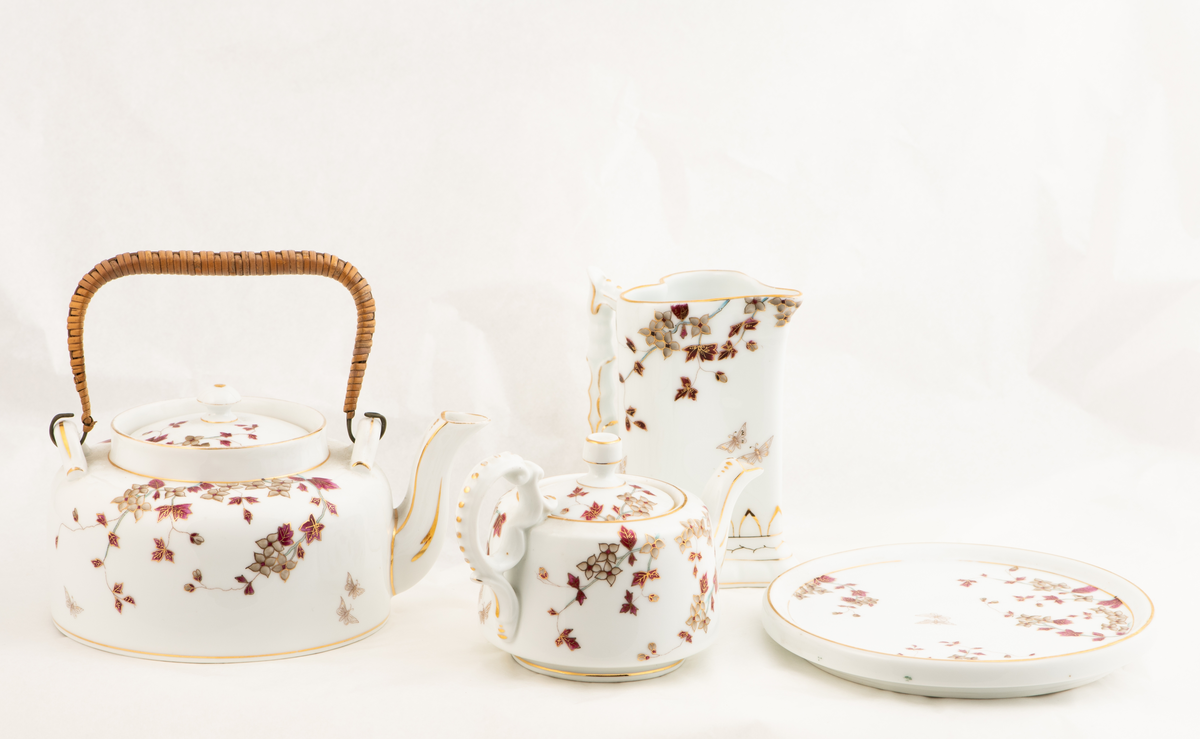 En porselenstallerken med påmalte blomster og to sommerfugler.